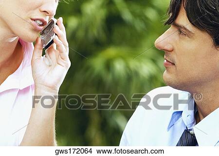 Close-up of a businesswoman talking on a mobile phone and a businessman looking at her View Large Photo Image Picture - Close-up of a businesswoman talking on a mobile phone and a businessman looking at her. Fotosearch