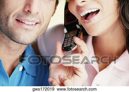 Close-up of a young couple using a mobile phone View Large Photo Image Stock Photo - Close-up of a young couple using a mobile phone. Fotosearch