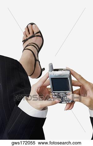 Stock Photography - Low section view of a businesswoman operating a mobile phone. Fotosearch
