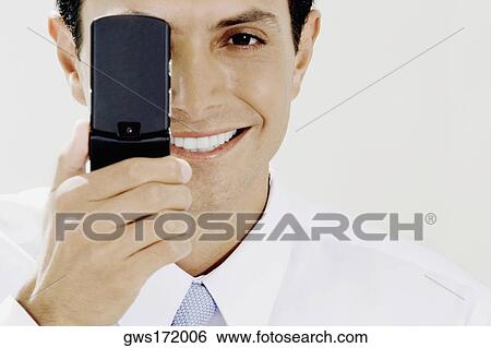 Portrait of a businessman covering his eye with a mobile phone View Large Photo Image Stock Photograph - Portrait of a businessman covering his eye with a mobile phone. Fotosearch