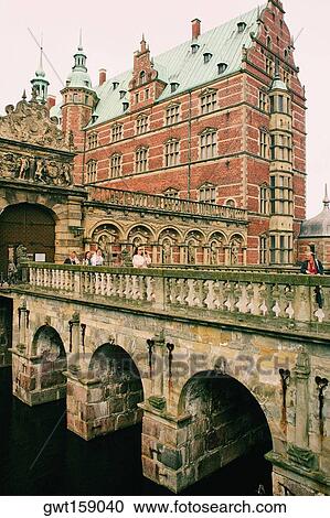 Stock Image - Group of people on the bridge in front of a castle, Frederiksborg Castle, Hillerod, Denmark. Fotosearch