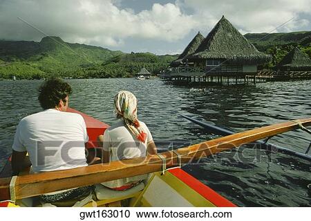 Stock Image - Rear view of a man and woman in a boat, Raiatea Island, Tahiti, Society Islands, French Polynesia. Fotosearch