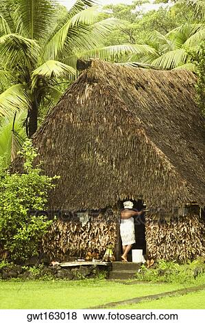 Stock Photo - Rear view of a woman standing at the door of hut, Vanua Levu, Fiji. Fotosearch