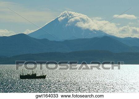 Boat in the river with a volcano in the background, Viluchinsky Volcano, Bay of Petropavlovsk, Kamchatka, Russia View Large Photo Image Stock Image - Boat in the river with a volcano in the background, Viluchinsky Volcano, Bay of Petropavlovsk, Kamchatka, Russia. Fotosearch