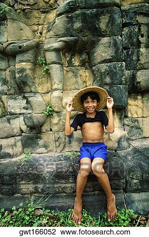 Boy sitting on a ledge and smiling, Angkor Thom, Angkor, Siem Reap, Cambodia View Large Photo Image Stock Image - Boy sitting on a ledge and smiling, Angkor Thom, Angkor, Siem Reap, Cambodia. Fotosearch