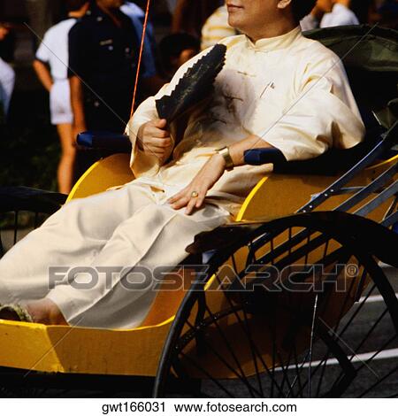 Stock Image - Close-up of a mid adult man sitting on a rickshaw, Singapore. Fotosearch
