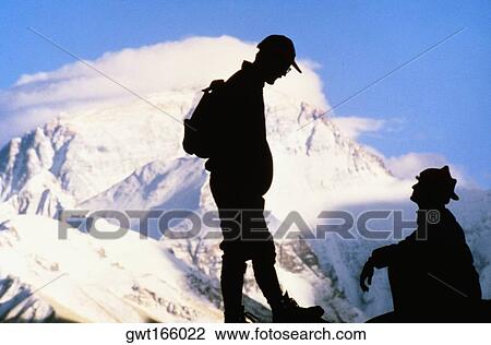 Silhouette of two men on a mountain with snow covered mountains in the background, Mt Everest, Tibet, China View Large Photo Image Stock Image - Silhouette of two men on a mountain with snow covered mountains in the background, Mt Everest, Tibet, China. Fotosearch