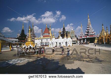 Stock Image - Pilgrims in front of a pagoda, Shwedagon Pagoda, Yangon, Myanmar. Fotosearch