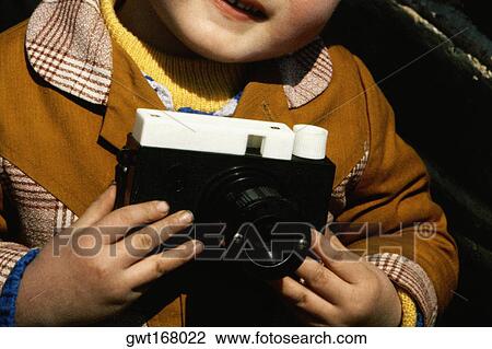 Stock Image - Mid section view of a boy holding a camera, Great Wall Of China, Beijing, China. Fotosearch