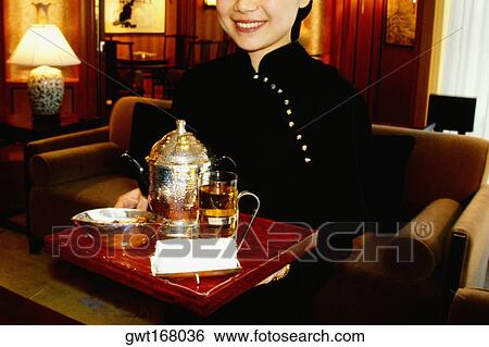Stock Photograph - Waitress holding a serving tray and smiling, Shanghai, China. Fotosearch