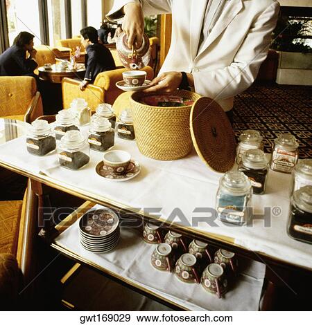 Stock Photo - Mid section view of a man pouring tea into a cup, Hong Kong, China. Fotosearch