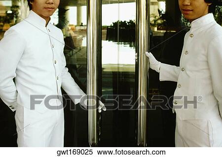 Stock Photography - Two porters standing at the entrance of a hotel doors, Regent Hotel, Kowloon, Hong Kong, China. Fotosearch