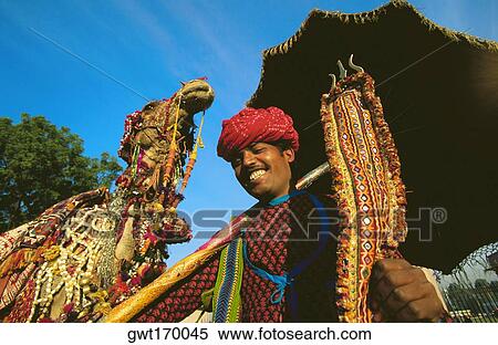 Young man holding a trident and standing near a camel, Jaipur, Rajasthan, India View Large Photo Image Stock Photography - Young man holding a trident and standing near a camel, Jaipur, Rajasthan, India. Fotosearch