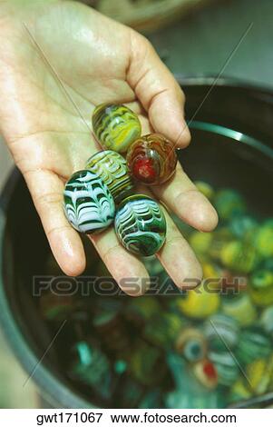 Stock Photo - Close-up of a person's hand holding marbles. Fotosearch