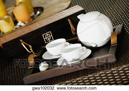 Stock Image - Close-up of a teapot with teacups on a serving tray. Fotosearch