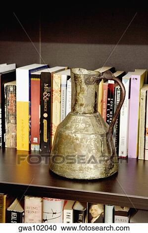 Close-up of an old pitcher in front of books in a shelf View Large Photo Image Stock Image - Close-up of an old pitcher in front of books in a shelf. Fotosearch