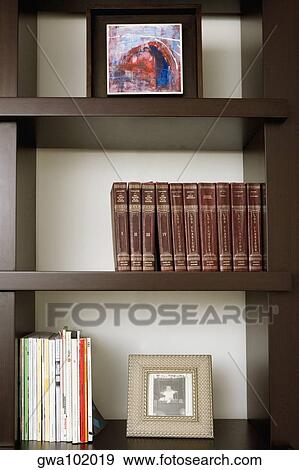 Stock Photo - Close-up of books and picture frames in shelves. Fotosearch