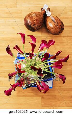 Stock Photography - High angle view of flowers in a vase on a stack of books with dried gourds. Fotosearch