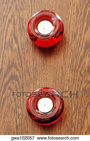 Stock Photo - High angle view of two candles in candlestick holders on a table. Fotosearch