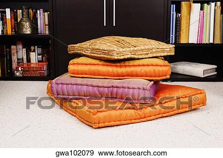 Stock Photo - Stack of cushions in front of a cabinet. Fotosearch