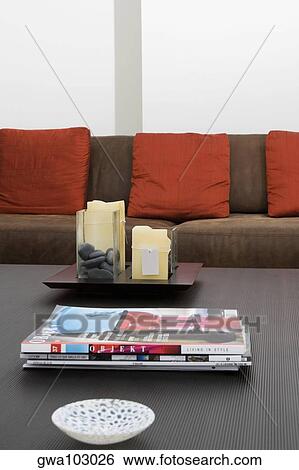 Bowl and magazines on a table in front of a couch View Large Photo Image Stock Photograph - Bowl and magazines on a table in front of a couch. Fotosearch