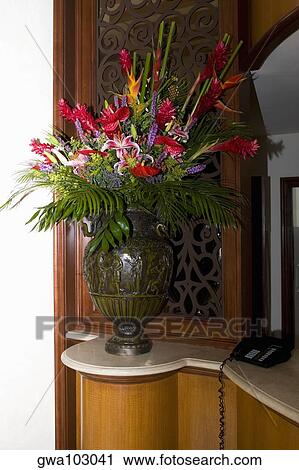 Stock Image - Flower vase and a telephone on a cabinet. Fotosearch