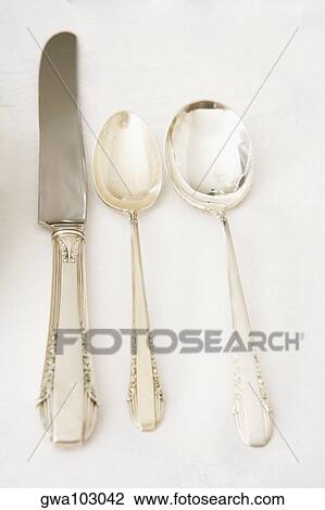 Stock Image - Table knife with two spoons on a dining table. Fotosearch