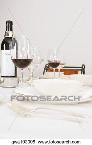 Stock Photography - Wine bottle and wine glasses with tableware on a dining table. Fotosearch