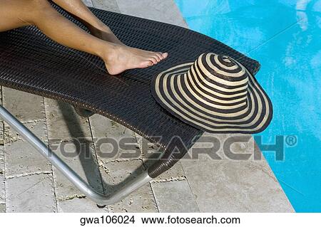 Picture - Low section view of a person on a lounge chair at the poolside. Fotosearch