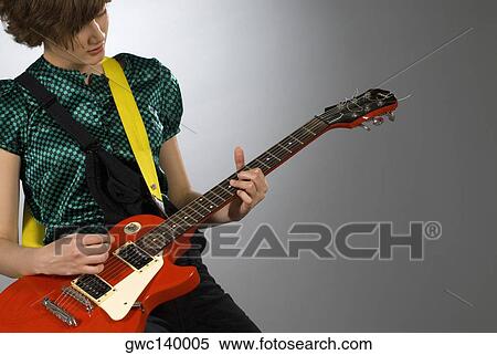 Close-up of a female guitarist playing a guitar View Large Photo Image Stock Photography - Close-up of a female guitarist playing a guitar. Fotosearch