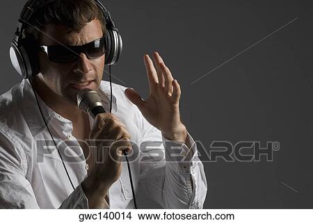 Close-up of a young man singing into a microphone View Large Photo Image Picture - Close-up of a young man singing into a microphone. Fotosearch