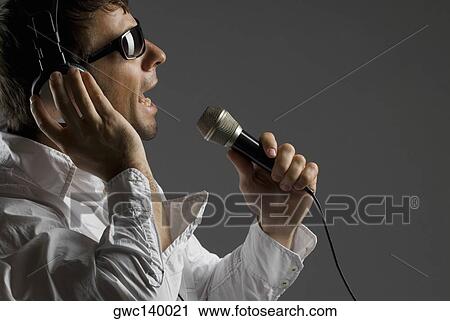Close-up of a young man singing into a microphone View Large Photo Image Stock Image - Close-up of a young man singing into a microphone. Fotosearch