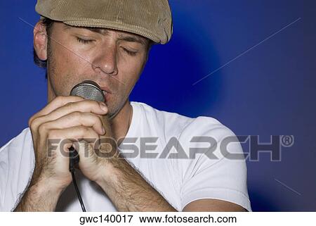 Close-up of a young man singing into a microphone View Large Photo Image Stock Photo - Close-up of a young man singing into a microphone. Fotosearch
