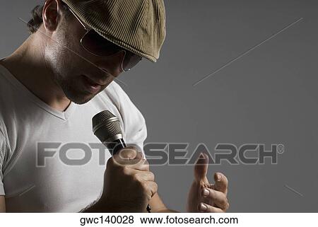 Close-up of a young man singing into a microphone View Large Photo Image Stock Photo - Close-up of a young man singing into a microphone. Fotosearch