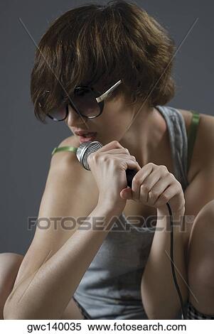 Close-up of a young woman singing into a microphone View Large Photo Image Stock Photography - Close-up of a young woman singing into a microphone. Fotosearch