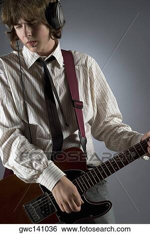 Close-up of a guitarist playing a guitar View Large Photo Image Stock Photograph - Close-up of a guitarist playing a guitar. Fotosearch