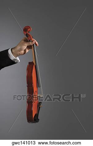 Stock Image - Close-up of a person's hand holding a violin. Fotosearch
