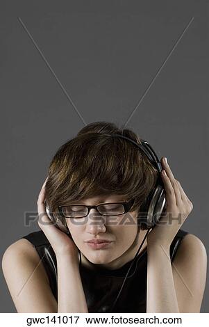 Close-up of a young woman listening to music View Large Photo Image Stock Photo - Close-up of a young woman listening to music. Fotosearch
