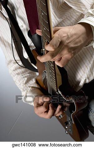 Mid section view of a male guitarist playing a guitar View Large Photo Image Stock Photo - Mid section view of a male guitarist playing a guitar. Fotosearch