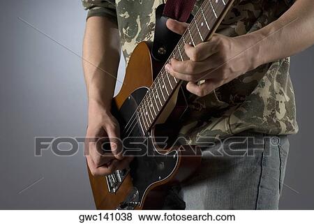 Mid section view of a male guitarist playing a guitar View Large Photo Image Stock Photo - Mid section view of a male guitarist playing a guitar. Fotosearch
