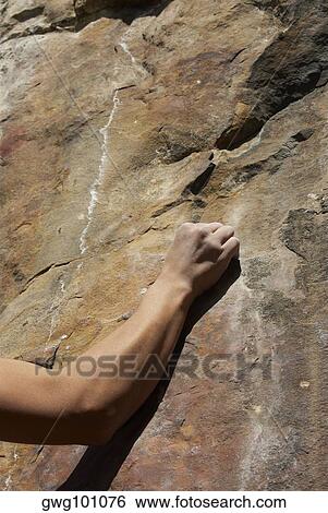 Close-up of a human arm gripping a rock View Large Photo Image Stock Photograph - Close-up of a human arm gripping a rock. Fotosearch