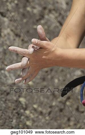 Stock Photo - Close-up of a rock climber rubbing chalk powder on her hands. Fotosearch
