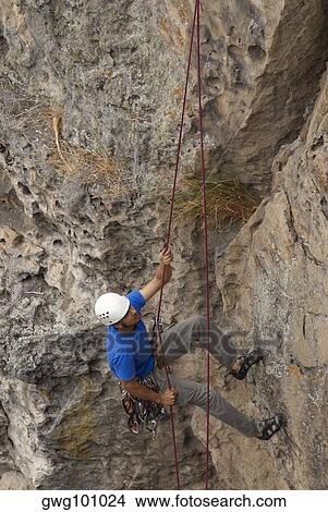 High angle view of a male rock climber scaling a rock face with a rope View Large Photo Image Picture - High angle view of a male rock climber scaling a rock face with a rope. Fotosearch