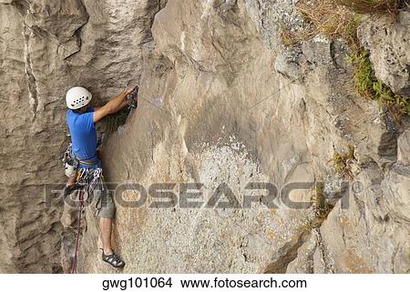 High angle view of a male rock climber hinging a rope on a rock View Large Photo Image Picture - High angle view of a male rock climber hinging a rope on a rock. Fotosearch