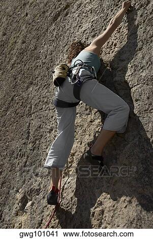 Low angle view of a female rock climber scaling a rock face View Large Photo Image Stock Image - Low angle view of a female rock climber scaling a rock face. Fotosearch