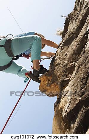 Low angle view of a female rock climber scaling a rock face View Large Photo Image Stock Image - Low angle view of a female rock climber scaling a rock face. Fotosearch