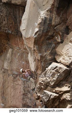 Stock Photo - Low angle view of a female rock climber scaling a rock face. Fotosearch