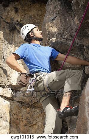 Low angle view of a male rock climber scaling a rock face View Large Photo Image Stock Photography - Low angle view of a male rock climber scaling a rock face. Fotosearch