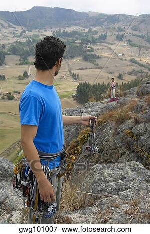 Stock Photo - Male rock climber looking at a female rock climber standing on a rock. Fotosearch