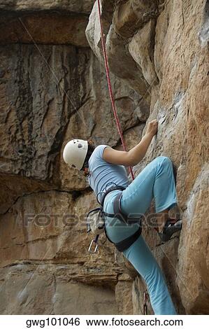Rear view of a female rock climber ascending a rock face View Large Photo Image Stock Photograph - Rear view of a female rock climber ascending a rock face. Fotosearch